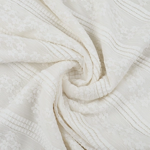 Detailed close-up of cream lace fabric with floral embroidery and vertical textures