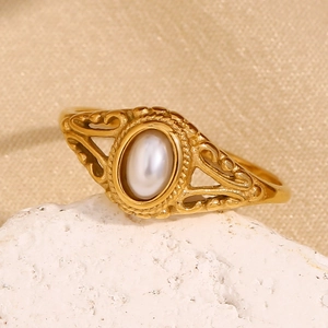 Detail of a gold floral ring with oval pearl on white stone and beige fabric texture