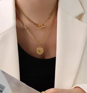 Close-up of layered 18k gold plated stainless steel necklace with round pendant and gun motif