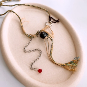 Détail d'un collier ethnique en corde tressée avec chaîne en argent et perle d'agate