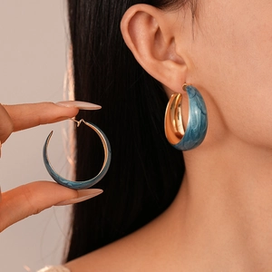 Blue marble texture resin C-shaped wide hoop earrings shown on a model and hand