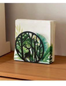 Detail view of a matte black metal napkin holder featuring a laser-cut forest and elk design