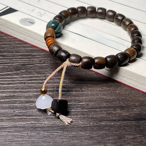 Dark brown wood bead bracelet with green pumpkin bead and white lotus charm on book