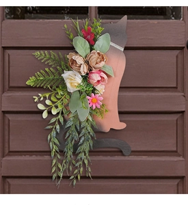 Detailed view of a black cat silhouette wall hanging with peach roses and lush green leaves