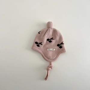 Detail of baby knitted hat showing cherry pattern, soft pink yarn, and plush earflap ties