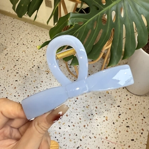 Hellblaue Haarklammer in Schleifenform aus Acryl mit goldfarbener Metallfeder