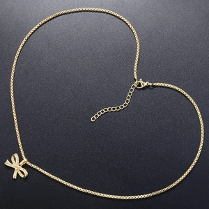 Detailed view of golden box chain necklace with a sparkling rhinestone bow pendant