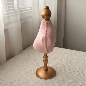 Macro view of pink fabric jewelry display bust with golden vintage style metal base