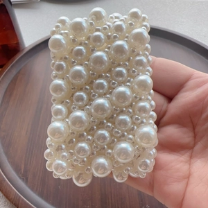 Detail showing hand-held rectangular faux pearl accessory on a dark wooden tray