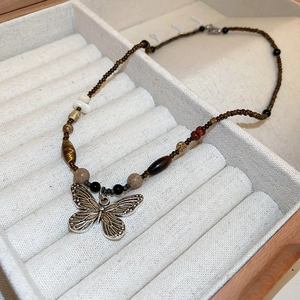 Detailed view of beaded necklace featuring a silver butterfly pendant in a jewelry box
