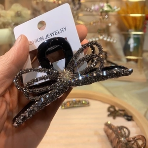Sparkling rhinestone bow hair claw clip in dark grey metal finish for elegant styling
