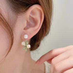 Boucles d'oreilles muguet élégantes avec perles et feuilles vertes sur un mannequin