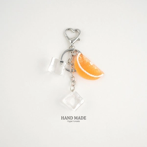 Detail of realistic orange slice keychain with metal heart clasp and ice cube charms
