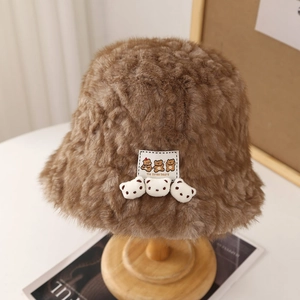 Close-up of brown plush bucket hat featuring three 3D bear ornaments and textile label