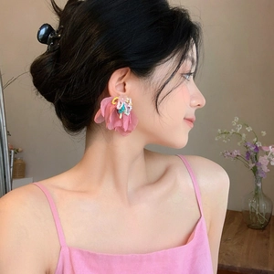 Primer plano de elegantes pendientes de gasa rosa con detalles de cuentas en modelo.