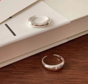 Detailed close-up of chunky 925 silver irregular ring on white book and wooden surface