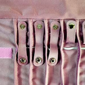 Detail of pink velvet jewelry roll organizer with metal snap buttons for necklaces