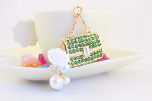 Detail of green rhinestone handbag keychain with white rose and pearls on gold metal