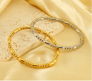 Close-up of gold and silver titanium steel beaded bracelets on a stone and silk background