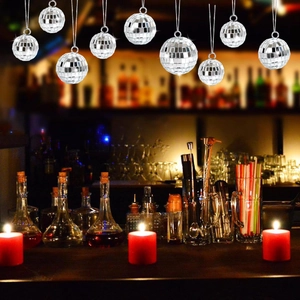 Silver mirror disco balls hanging over a bar counter with glowing red candles