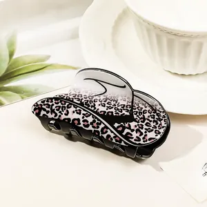 Detailed close-up of a pink leopard print acrylic claw clip with warm natural lighting
