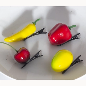Close-up of creative fruit and vegetable hair clips featuring chili and cherry shapes