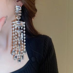 Close-up of sparkling silver tassel earrings with geometric crystals worn by a model