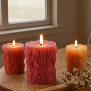 Macro shot of knitted texture cylindrical candles with warm glow on wooden table