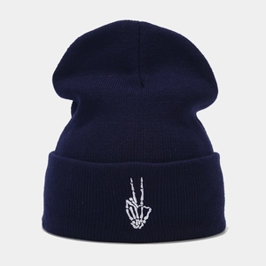 Détail de la broderie de main de squelette blanche sur un bonnet en tricot bleu marine