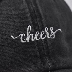 Vintage washed cotton baseball cap featuring white cheers embroidery on black fabric