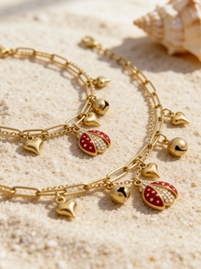 Détail d'un pendentif scarabée doré avec émail rouge et zircons sur fond de plage