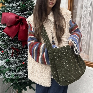 Detail of dark green plush polka dot shoulder bag paired with a fuzzy vest and sweater