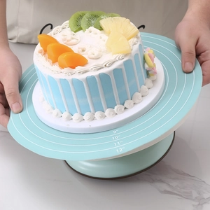 Blue cake turntable with size markings held by hands for home baking and decorating