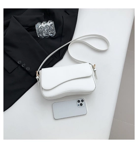 Detail of white leather shoulder bag with unique wavy flap and gold hardware