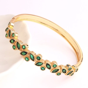 Macro detail of 18K gold plated geometric cuff featuring marquise cut green crystals
