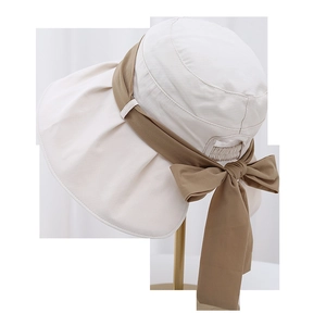 Détail d'un chapeau de soleil beige à large bord avec ruban kaki et nœud décoratif élégant