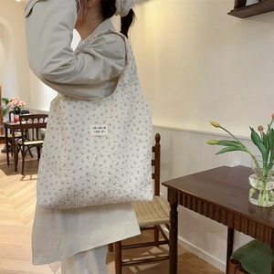 Detailed texture of beige floral tote bag with embossed fabric and brand logo patch