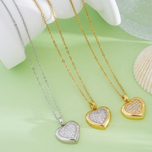 Three heart pendant necklaces in silver and gold finishes with diamonds on green satin