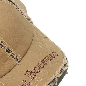 Close-up of distressed brim with leopard lining and red letter embroidery on baseball cap
