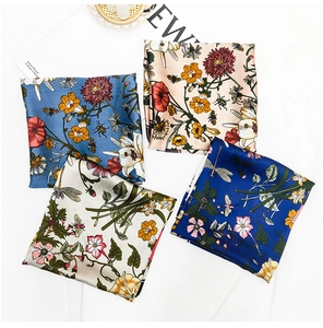 Flat lay of four colorful floral silk scarves with bee and dragonfly patterns on a desk
