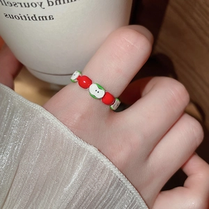Close-up of handmade beaded ring with a cute red apple pattern on a finger
