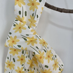 Detailed texture of cotton canvas wrist bag with yellow daisy floral patterns and knotted handle