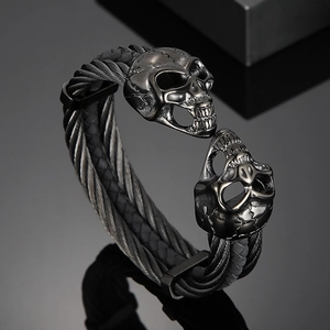 Macro view of gunmetal skull cuff bracelet with braided steel cable and gothic details