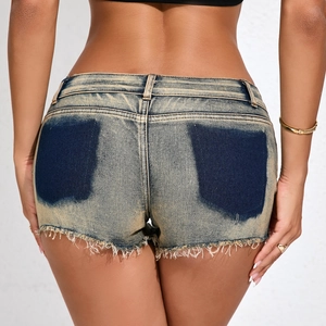Dettaglio di pantaloncini di denim a vita bassa blu vintage con orli sfilacciati e tasche