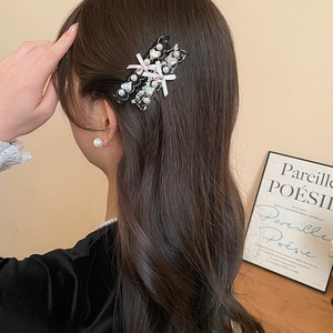 Close-up of pearl bow hair clip with black lace and pink heart gemstone on model