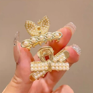 Detailed view of two gold alloy hair clips featuring elegant pearls and chain designs
