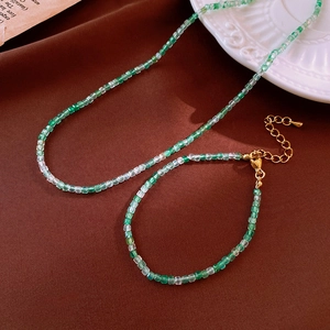 Detail of green and clear square bead jewelry set with gold lobster clasp and chain