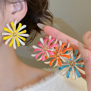 Dettaglio di orecchini a margherita colorati con petali in smalto e centro dorato