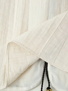 Close-up of beige textured fabric detail with vertical stripes and black drawstring