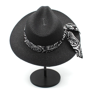 Detailed view of the black woven straw Panama hat with a paisley print ribbon bow